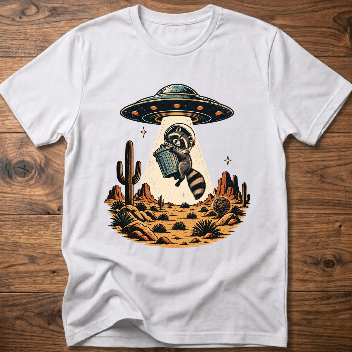 White crew-neck T-shirt with astronaut raccoon graphic, UFO, and desert cactus