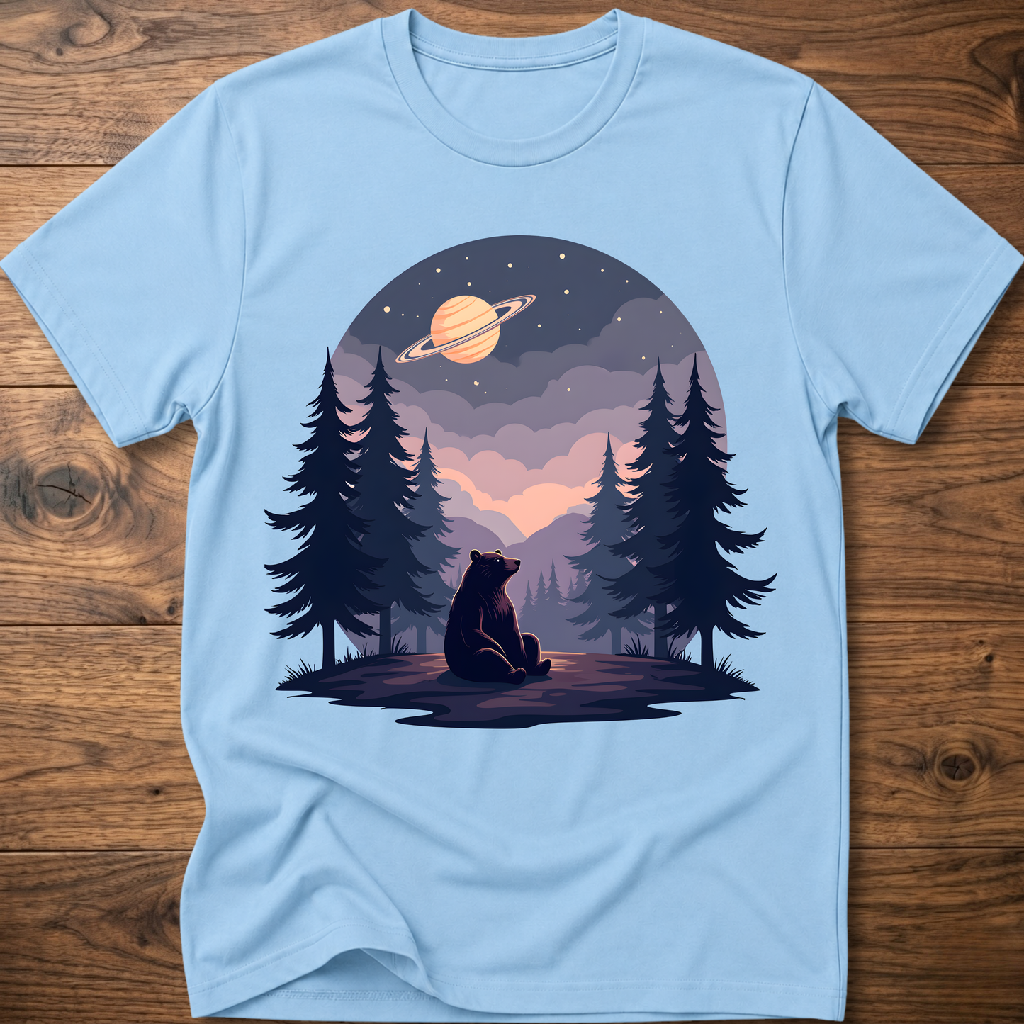 Light blue t-shirt with night sky bear graphic, ringed planet and pine trees on front
