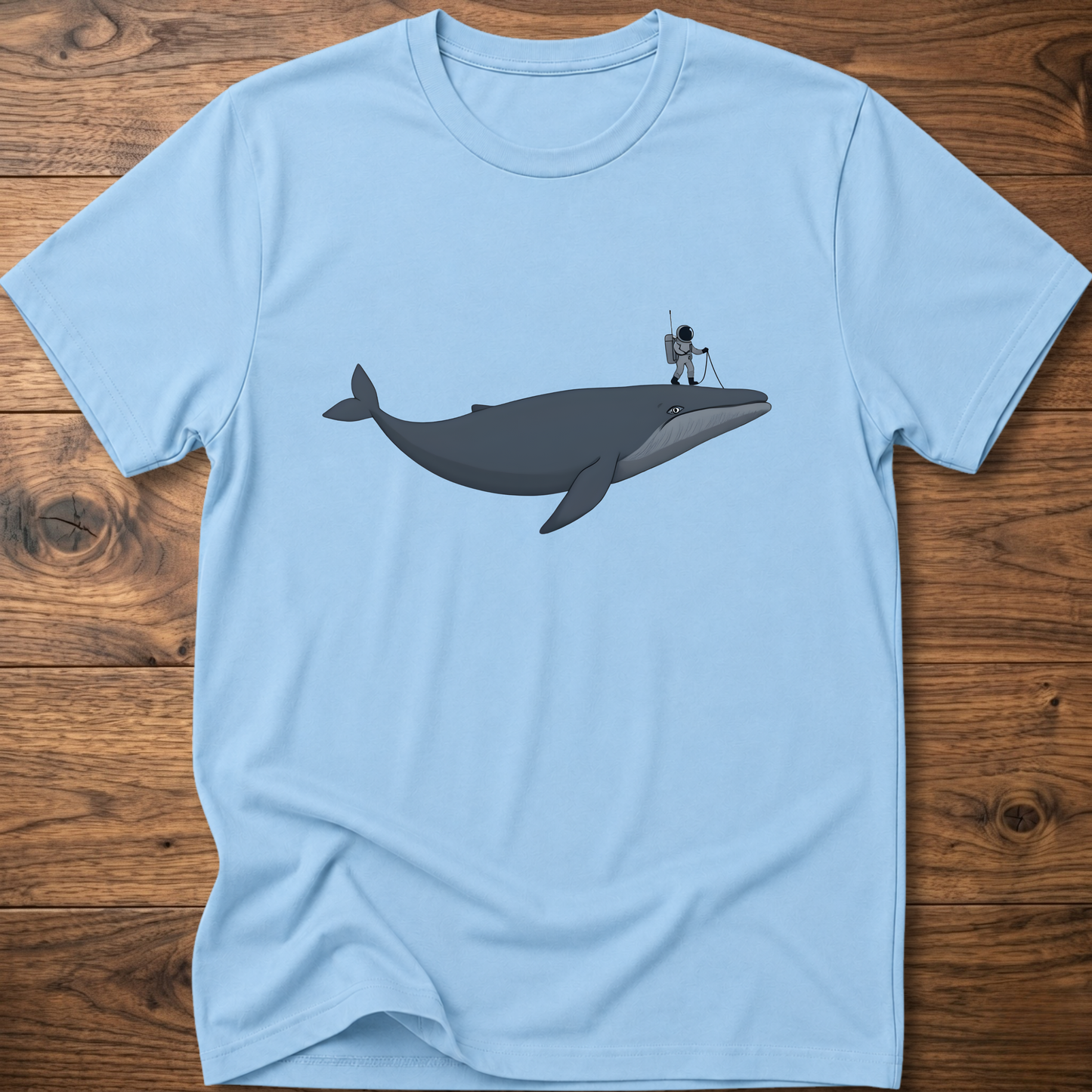 Light blue astronaut whale T-shirt with graphic whale and astronaut standing on back fin