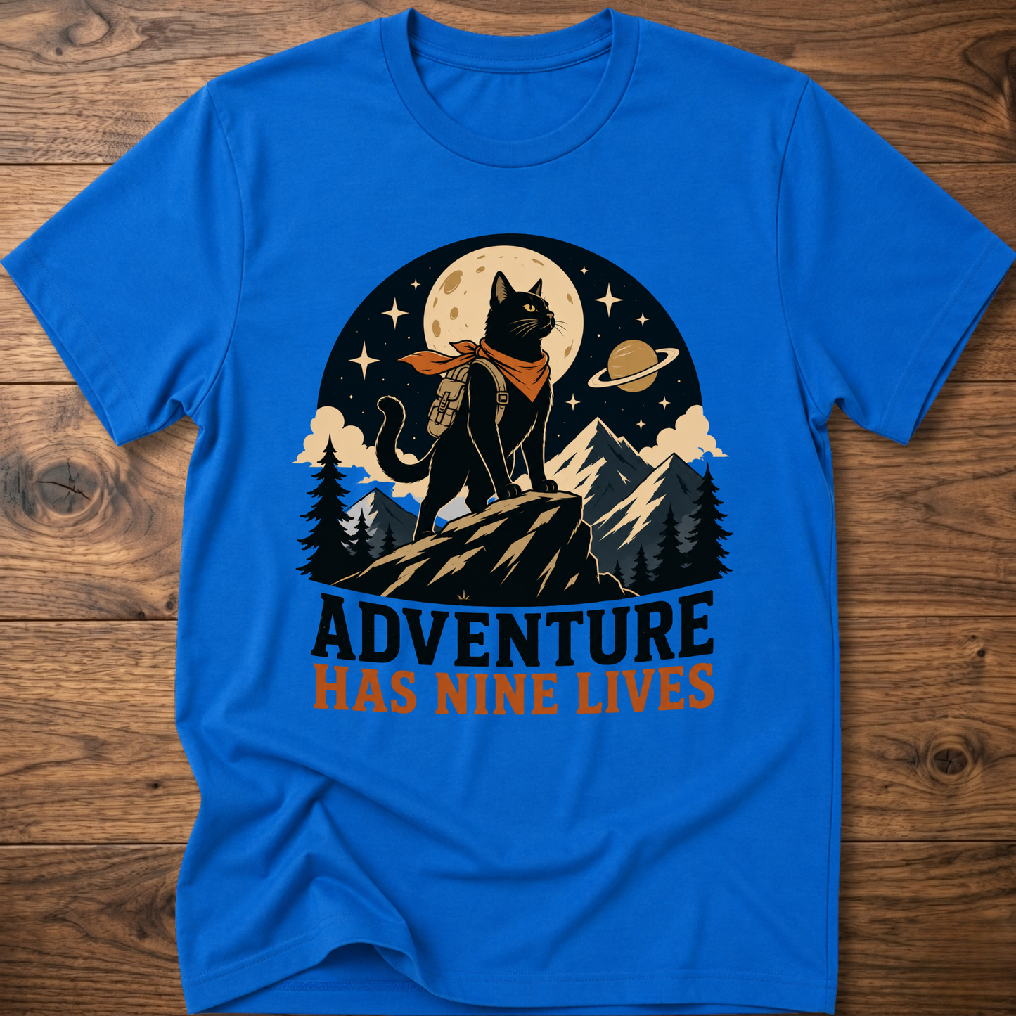 Royal blue cat graphic t-shirt, moonlit cat on mountains with 'Adventure Has Nine Lives'