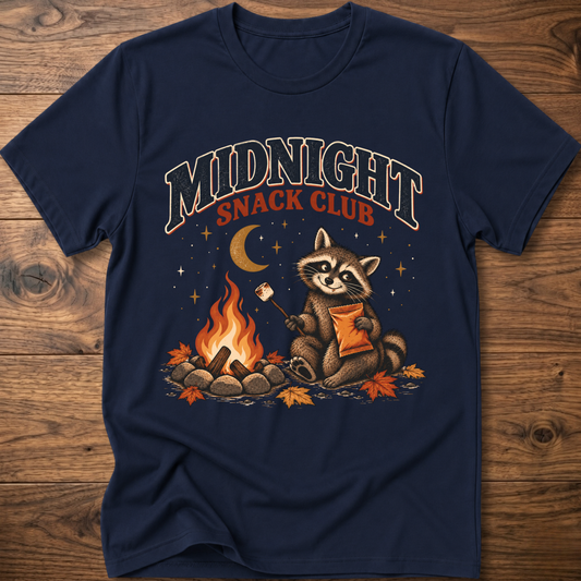 Navy T-shirt featuring “Midnight Snack Club” raccoon by a campfire with roasting marshmallow graphic