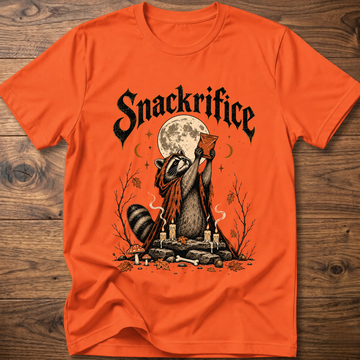 Orange crew-neck t-shirt with black 'Snackrifice' raccoon moon front graphic
