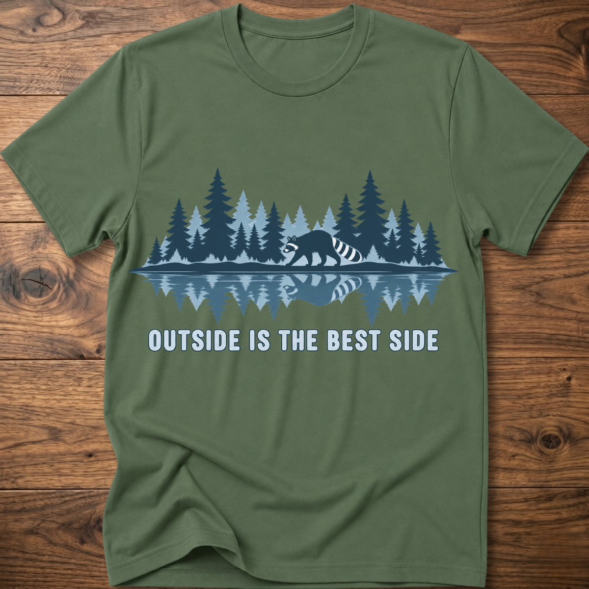 Olive green crew-neck T-shirt with blue raccoon tree scene graphic and “OUTSIDE IS THE BEST SIDE” text