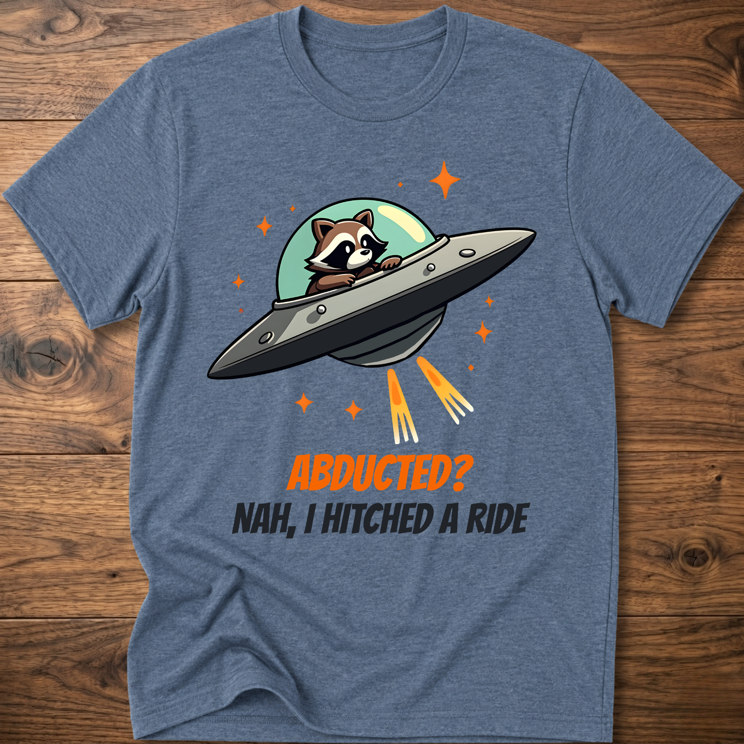 Heather blue raccoon graphic t-shirt with UFO and orange "ABDUCTED?" text