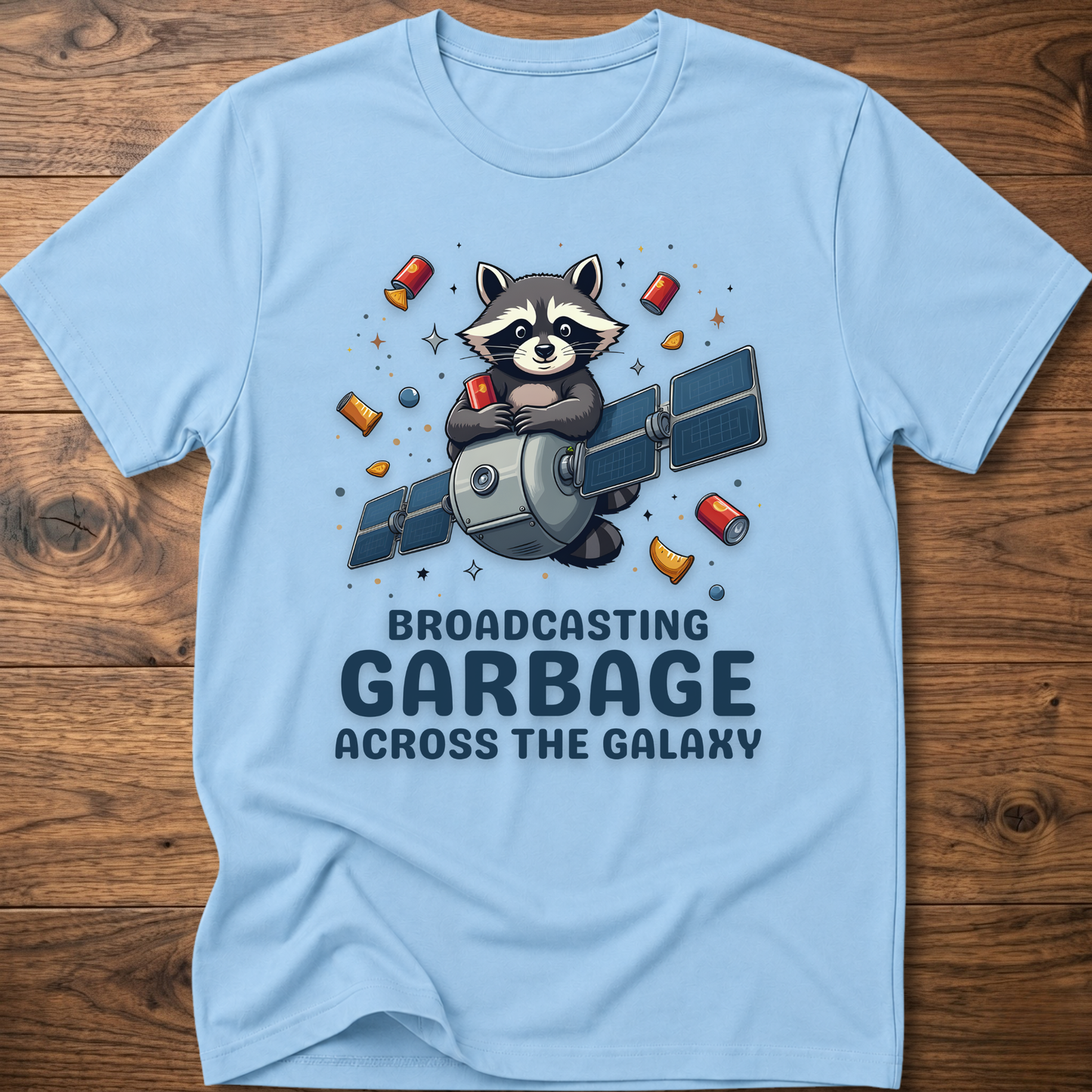 Light blue crew-neck T-shirt with raccoon holding megaphone graphic and “Broadcasting Garbage” text.