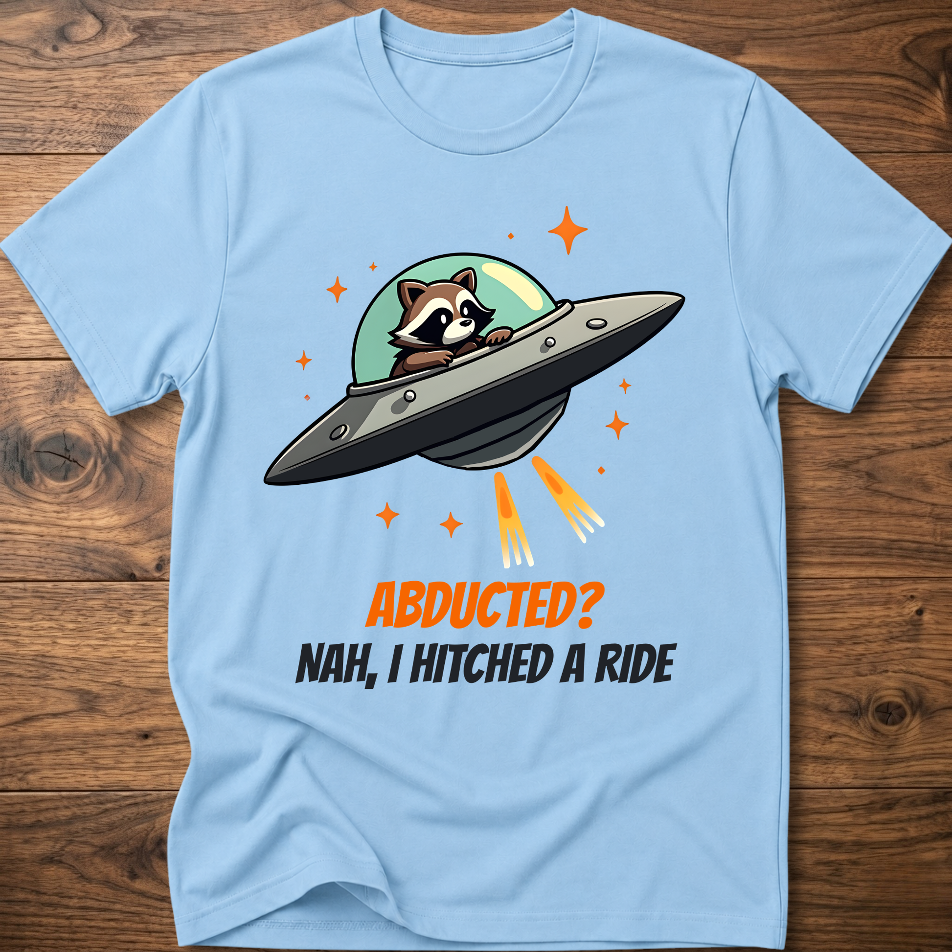 Light blue raccoon graphic t-shirt with UFO and orange "ABDUCTED?" text