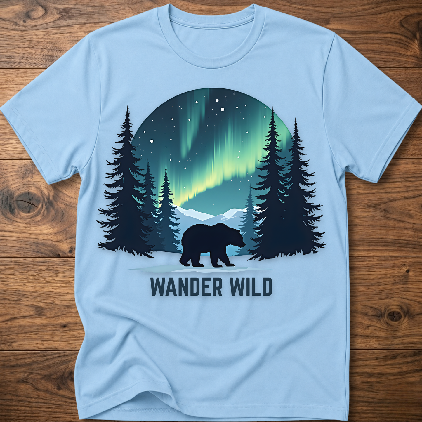 Light blue crew-neck t-shirt with bear in forest graphic and 'Wander Wild' text