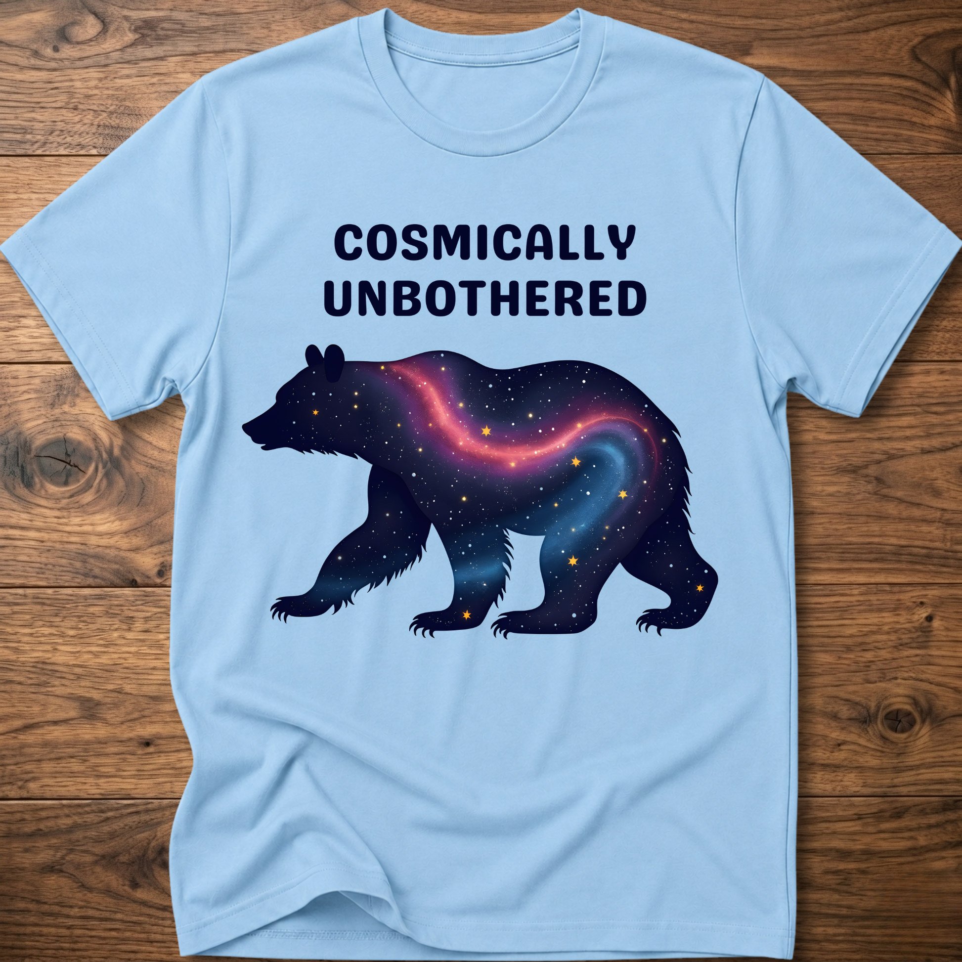 Light blue graphic t-shirt with cosmic bear and COSMICALLY UNBOTHERED lettering
