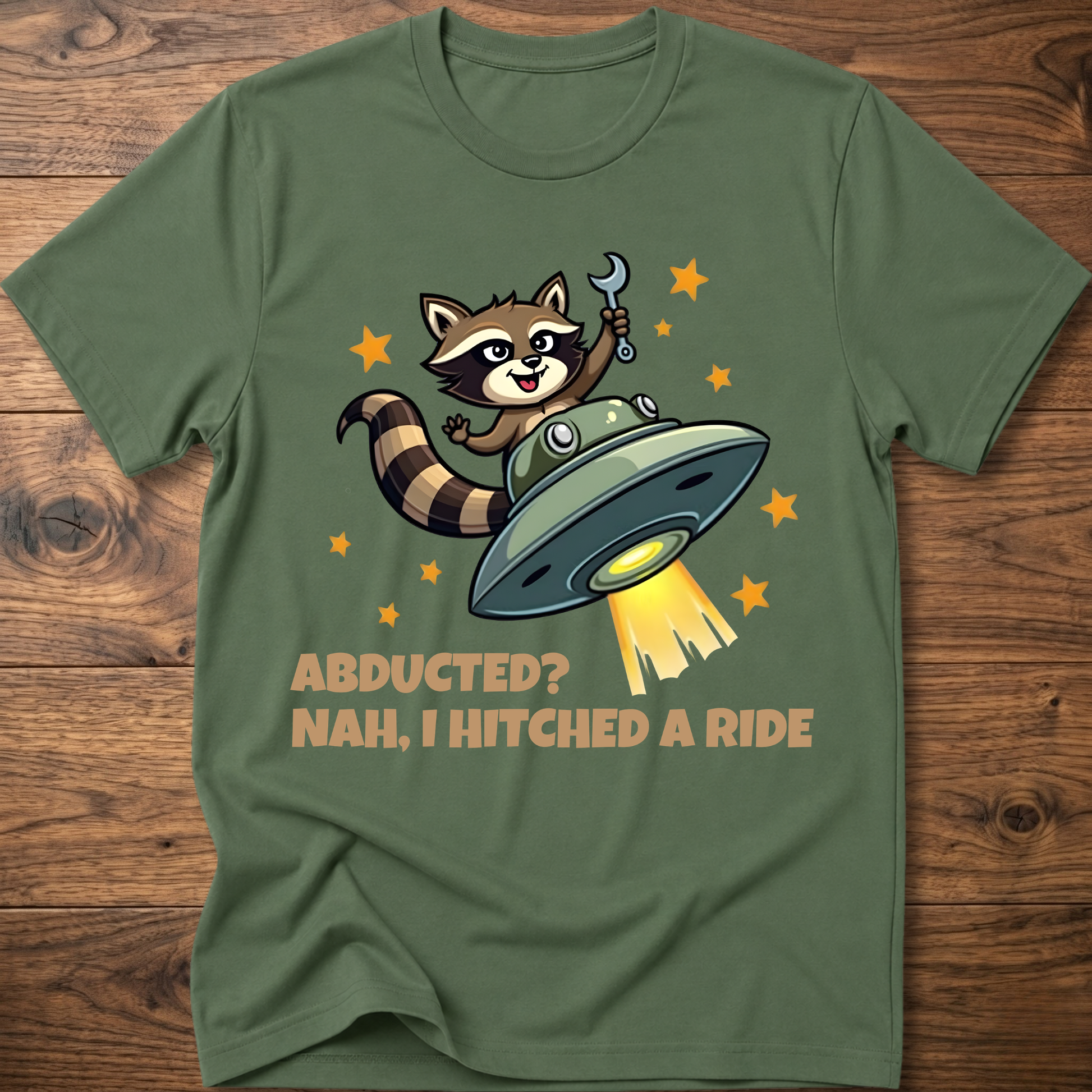 Military green raccoon UFO graphic T-shirt with 'ABDUCTED?' and 'HITCHED A RIDE' text