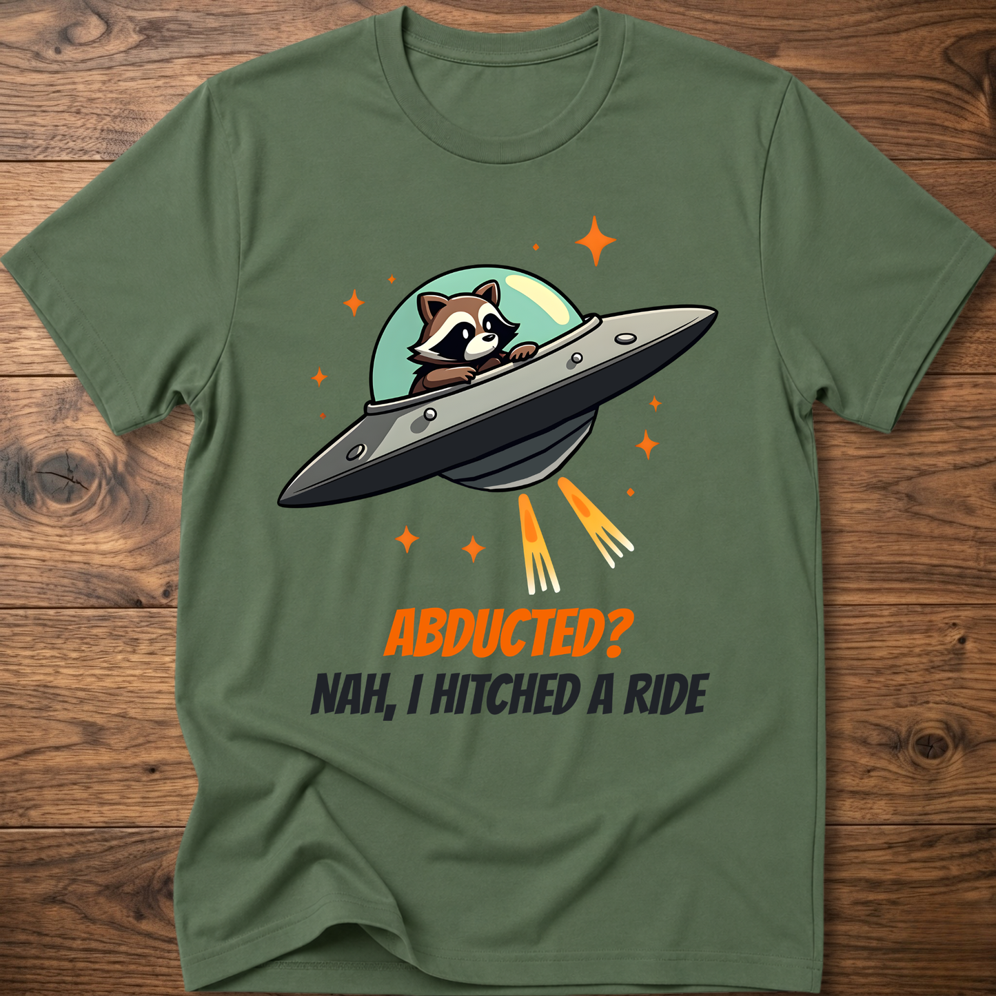 Olive green raccoon graphic t-shirt with UFO and orange "ABDUCTED?" text