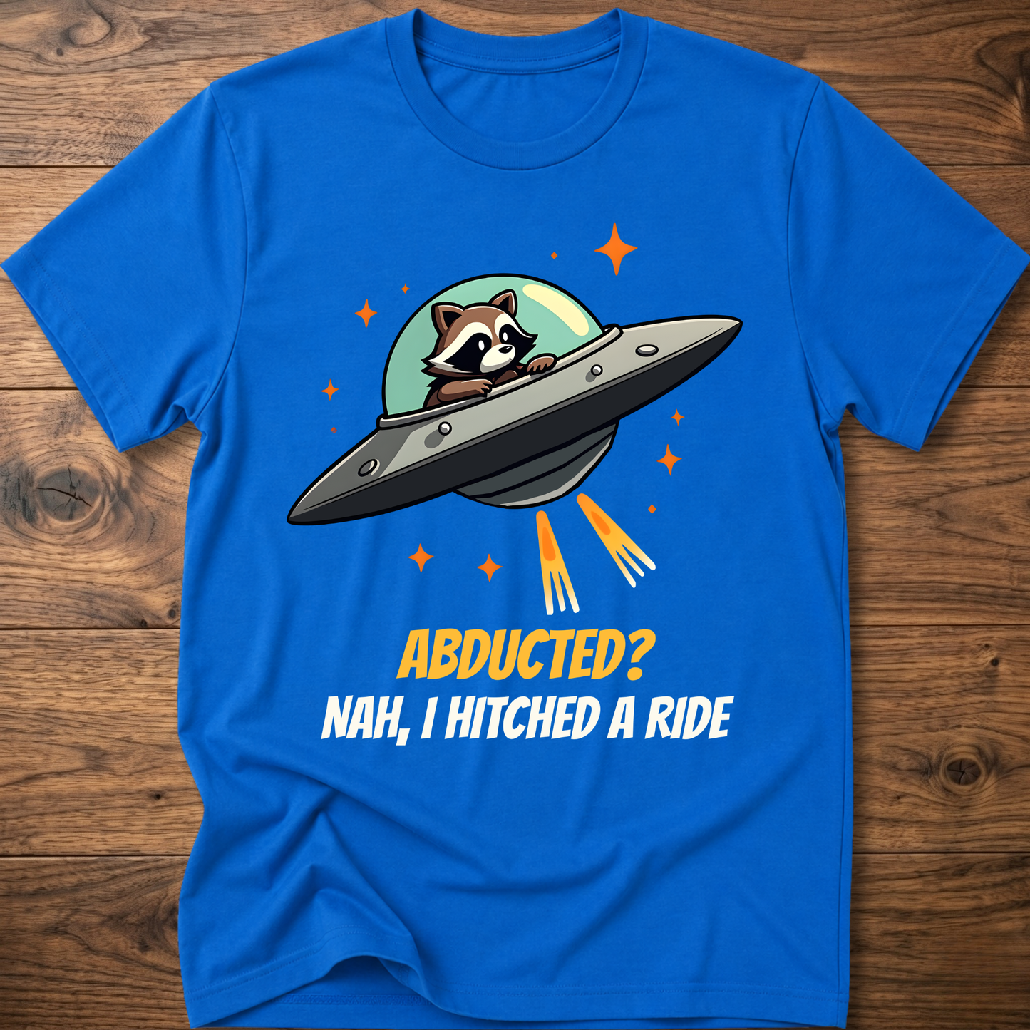 Royal blue raccoon graphic t-shirt with UFO and orange "ABDUCTED?" text