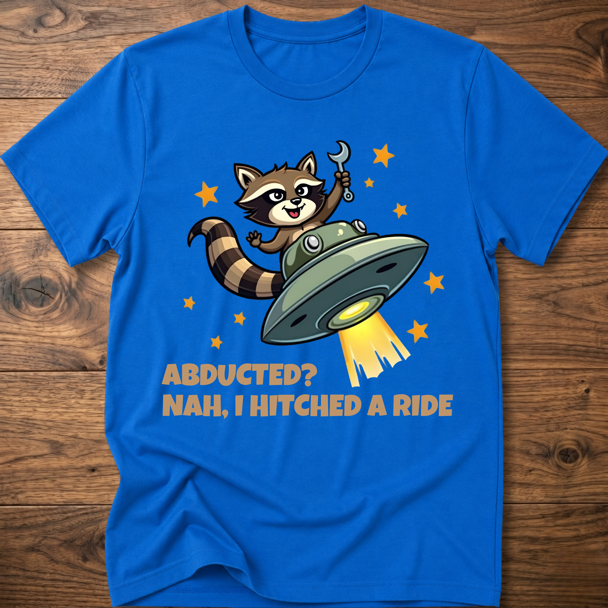 Royal blue raccoon UFO graphic T-shirt with 'ABDUCTED?' and 'HITCHED A RIDE' text