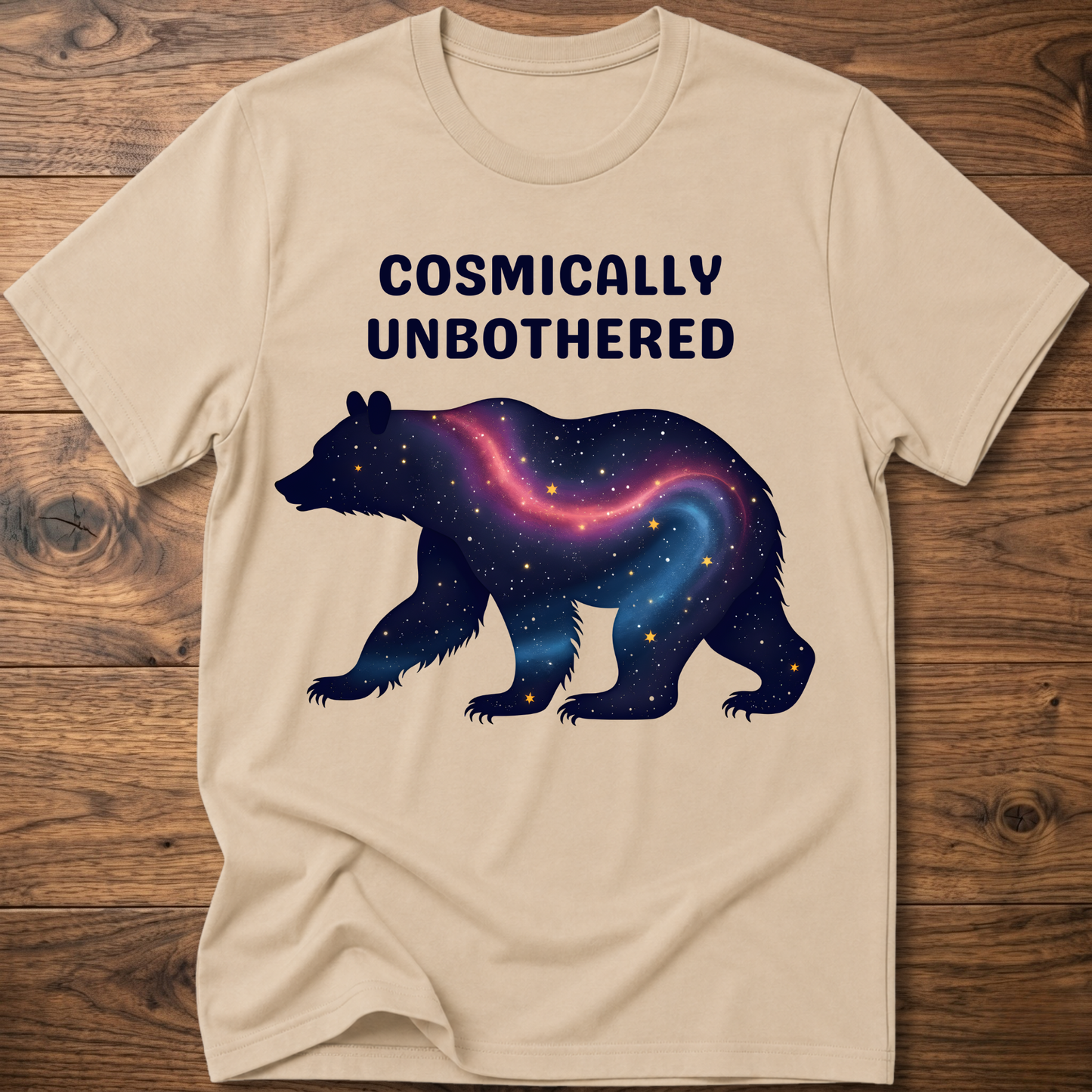 Sand graphic t-shirt with cosmic bear and COSMICALLY UNBOTHERED lettering