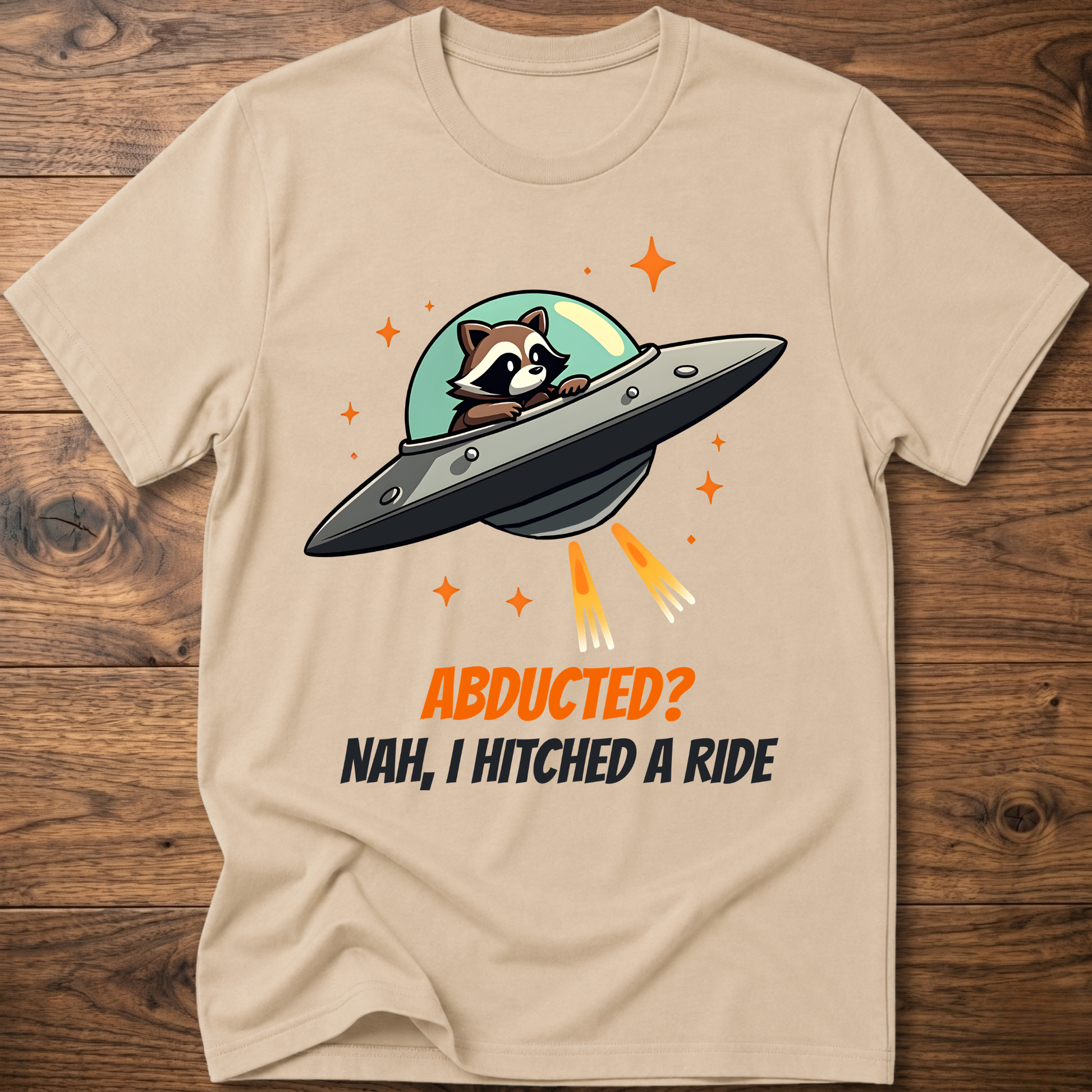 Sand raccoon graphic t-shirt with UFO and orange "ABDUCTED?" text