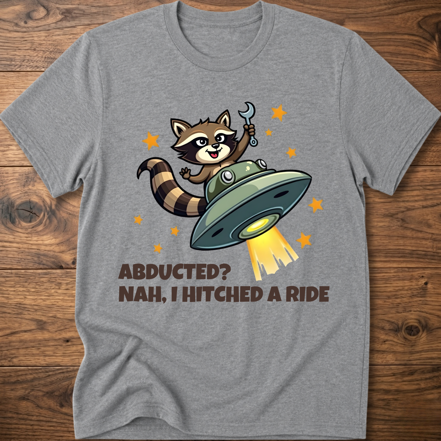 Heather gray raccoon UFO graphic T-shirt with 'ABDUCTED?' and 'HITCHED A RIDE' text