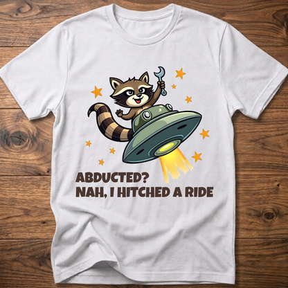 White raccoon UFO graphic T-shirt with 'ABDUCTED?' and 'HITCHED A RIDE' text